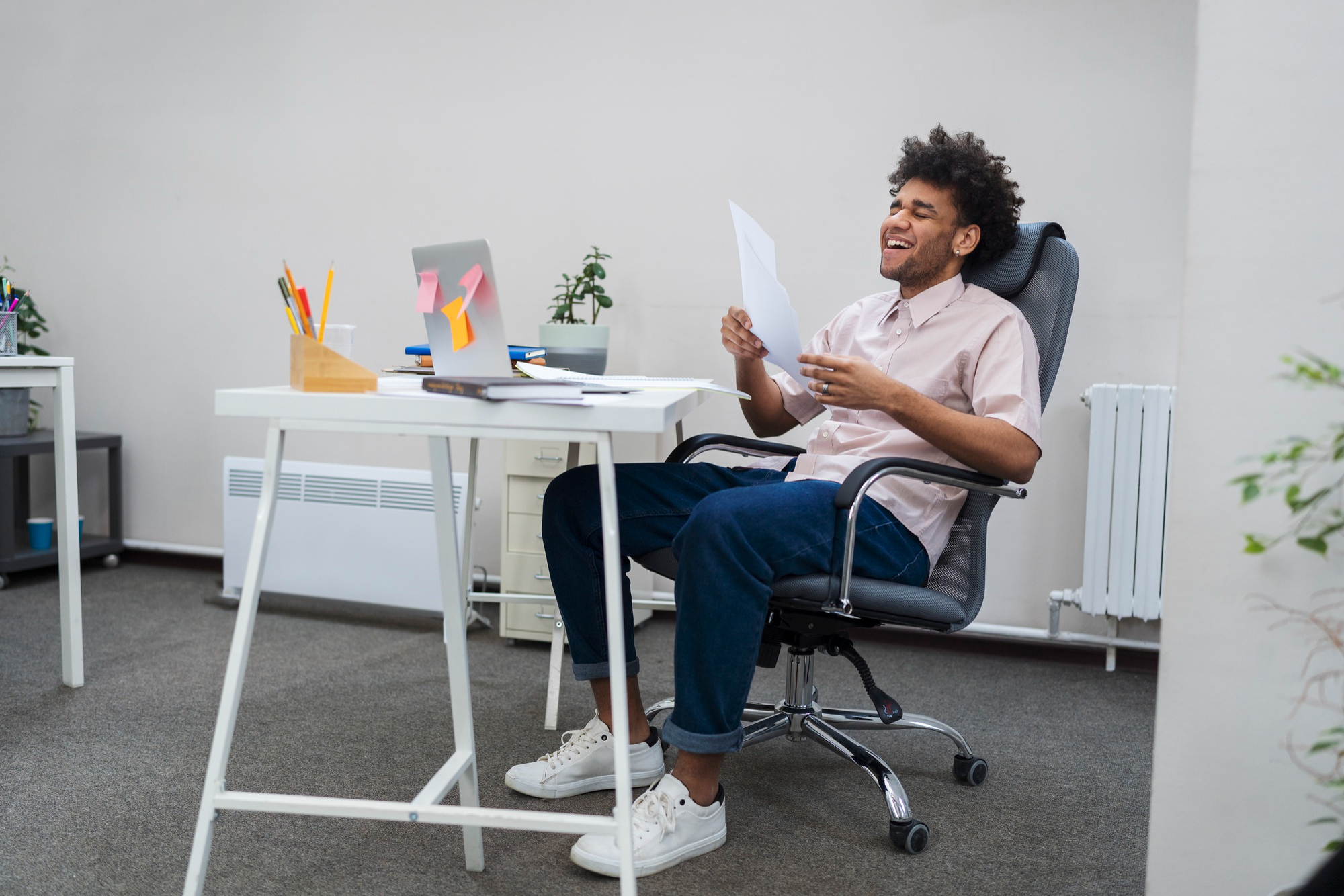 Person smiling while working at a desk, surrounded by colorful sticky notes and creative tools, reflecting a sense of joy and productivity.